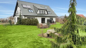 Ein zweistöckiges Haus mit Satteldach, einer Veranda und einem gepflegten Rasen.