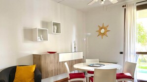A modern living room with a sofa, dining table, chairs, and a ceiling fan. - Seclusive Apartment in Sirmione near Lake (Sirmione)