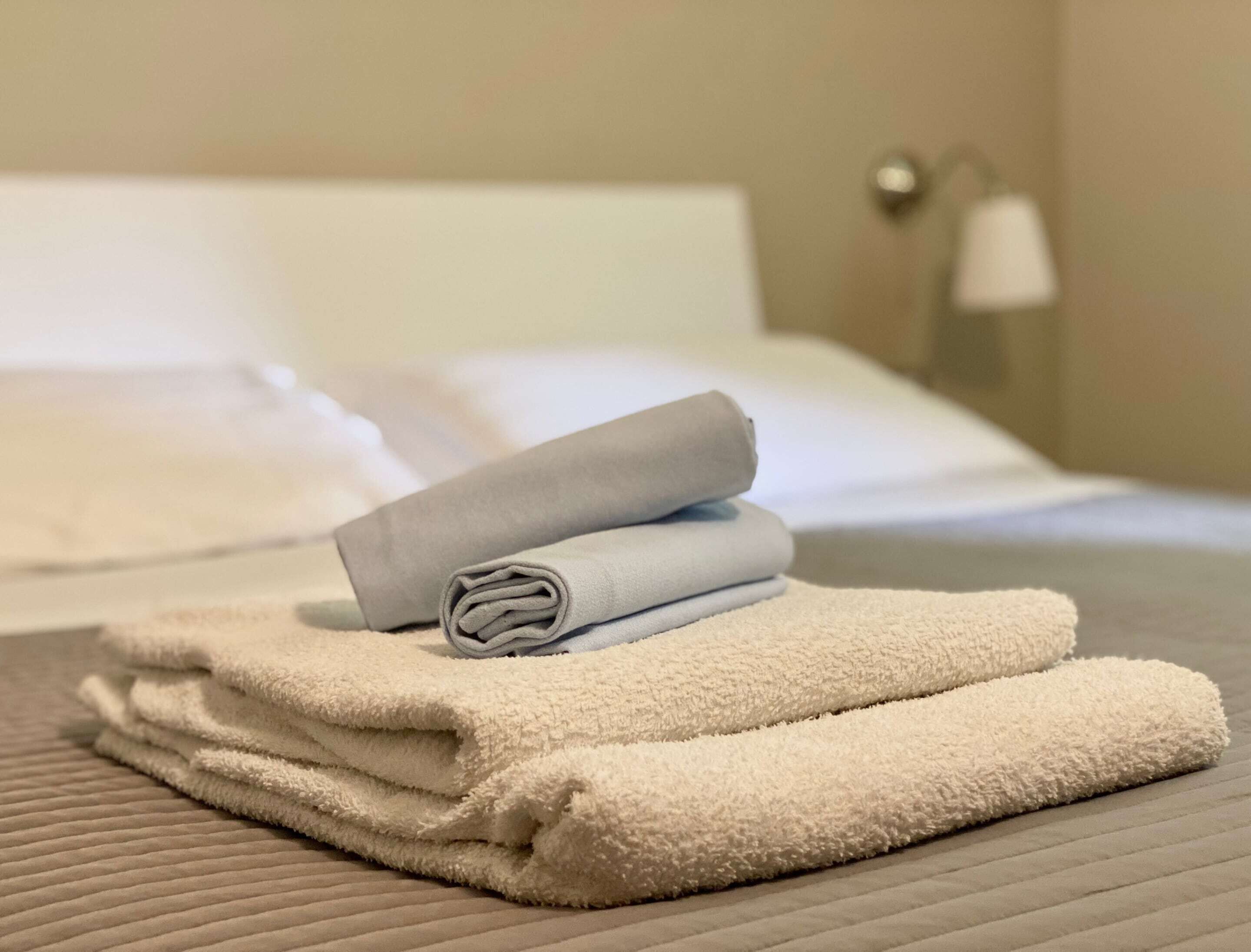 A neatly made bed with white and grey towels.