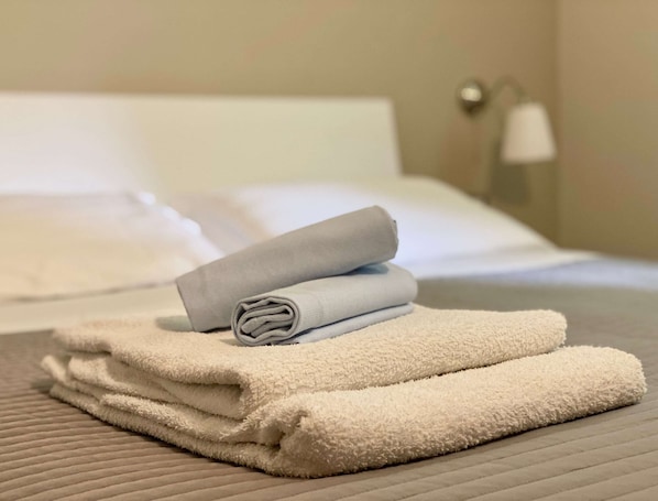 A neatly made bed with white and grey towels.