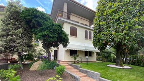 A house with a covered patio, a garden with a gravel pathway, and a lawn. - Seclusive Apartment in Sirmione near Lake (Sirmione)
