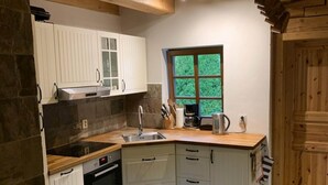 A compact kitchen with white cabinets, a built-in oven, a sink, and a window with a view of greenery.