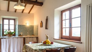 Eine Küche mit Esstisch für zwei Personen, einem Fenster mit Holzjalousien und einer gefliesten Spritzschutzwand.