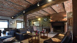 A cozy living area with leather sofas, a fireplace, and exposed brick walls. - Alluring Farmhouse in Lavacherie with Hot Tub (Sainte-Ode)