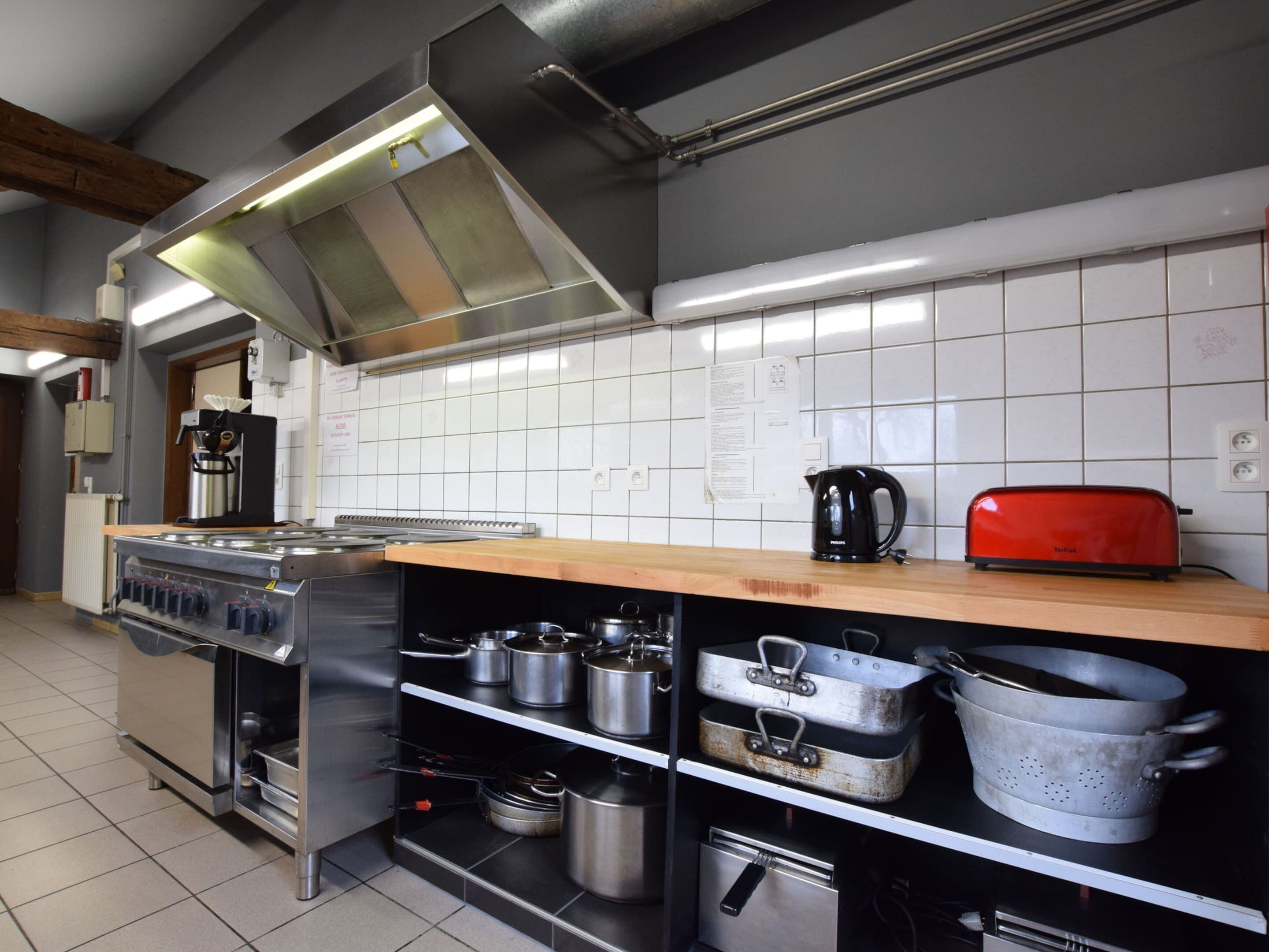 Una cocina industrial con electrodomésticos de acero inoxidable, una máquina de café y un tostador sobre la encimera.