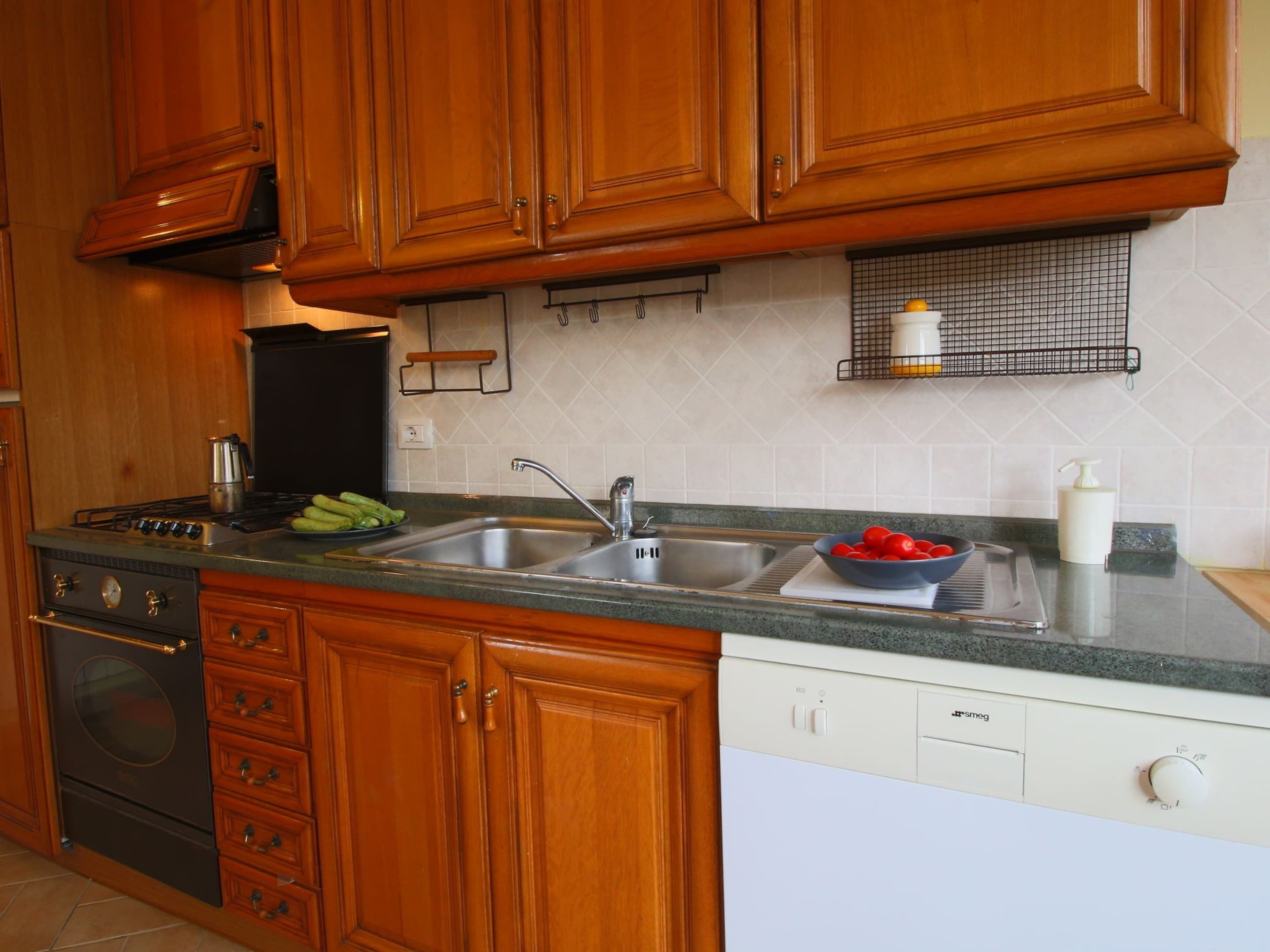 A kitchen with wooden cabinets, a stainless steel sink, a dishwasher, and a stove.