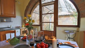 Mesa de jantar posta com pratos, talheres, um bule, um vaso com flores e velas.