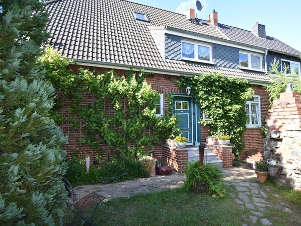 Stunning brick facade with a tiled roof, surrounded by a beautifully maintained garden and a charming entrance.
