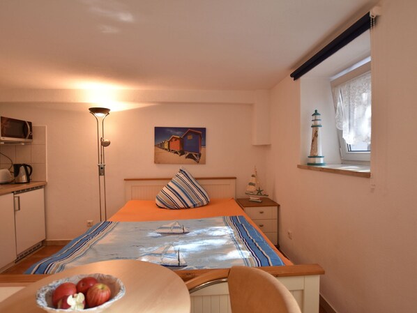 Une chambre à coucher avec un lit, une table de chevet, une lampe, un tableau, une fenêtre avec des rideaux et une vue sur la mer.