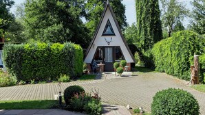 A small, triangular-shaped building with a sloped roof, surrounded by lush greenery and a paved pathway leading to it.