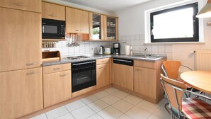 Eine moderne Küche mit Holzschränken, einem Einbauofen, einer Mikrowelle und einer Kaffeemaschine.