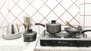 A kitchen with a gas stove, pots, pans, and utensils. - TC803 Vistão Av. Atlântica (Rio de Janeiro)