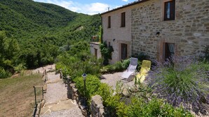 A stone building with a garden, a gravel path, and a mountainous backdrop. - Belvilla by OYO Sole e Luna (Pergola)