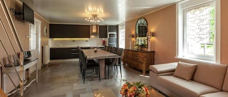 A modern kitchen with a dining area, a sofa, and a TV.