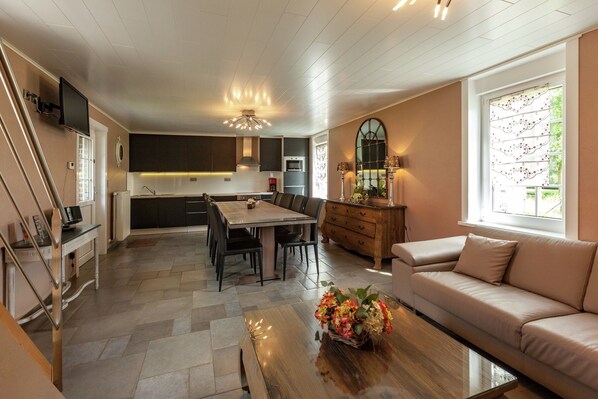 A modern kitchen with a dining area, a sofa, and a TV. - Le Bizet Vacation Home (Comines-Warneton)