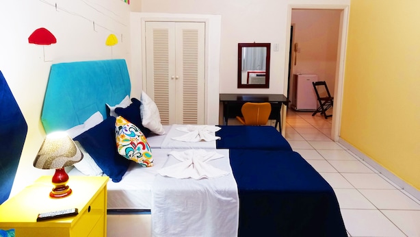 Une chambre d’hôtel comprenant un lit, une table de chevet, une lampe et un bureau avec une chaise.
