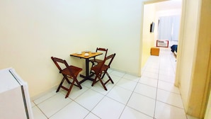 Une petite pièce propre, avec un sol carrelé, une table en bois et des chaises, et un mur blanc.