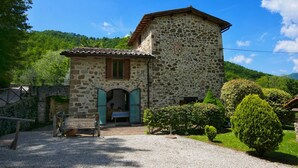 A stone building with a small porch and a wooden bench. - Holiday House with Pool & Large Garden Overlooking Lake near Tuscany (Lisciano Niccone)