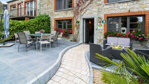 A stone building with a patio area featuring outdoor seating and a table. - Scenic Retreat in Gimnee (Doische)