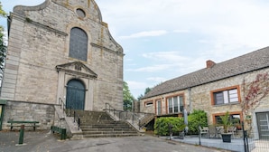 A historic stone building with a large arched window and a staircase leading to a door. - Scenic Retreat in Gimnee (Doische)