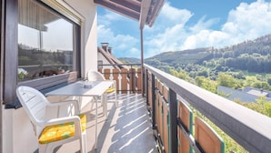 A balcony with a table and chairs, overlooking a scenic landscape with trees and hills. - Large Holiday Apartment near Willingen with Private Garden & Terrace (Medebach)
