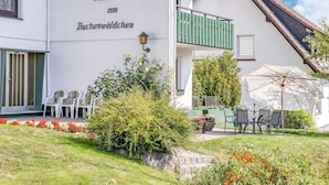 A building with a sign reading "Haus am Buchemwäldchen" and outdoor seating with tables and chairs. - Large Holiday Apartment near Willingen with Private Garden & Terrace (Medebach)