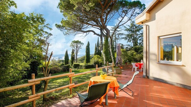 Un patio al aire libre con cerca de madera, una mesa con sillas y vista a un paisaje montañoso.