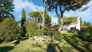 Una casa con muro de piedra, césped y árboles.