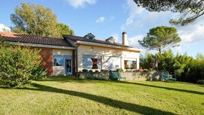 Una casa de dos pisos con tejado de baldosas, fachada de ladrillo y césped bien cuidado.
