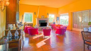 Un salón amplio con chimenea, varias zonas de estar y grandes ventanales.