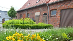 Een gebouw van baksteen met een rode dakbedekking, een houten deur en een bruine garagepoort.