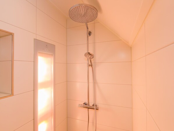 A shower with a handheld showerhead and a wall-mounted faucet.