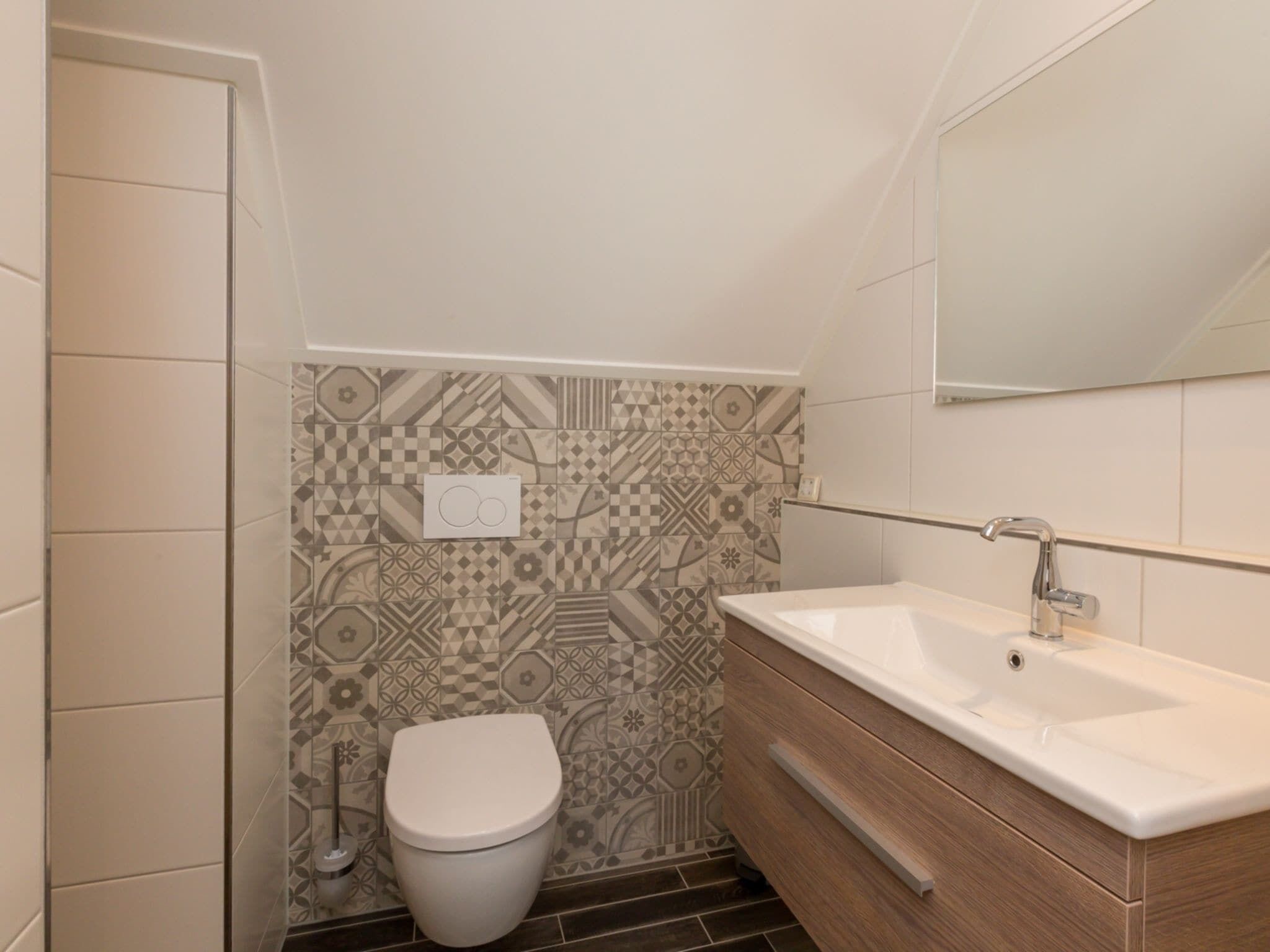 A modern bathroom with a toilet, sink, and patterned tiles.