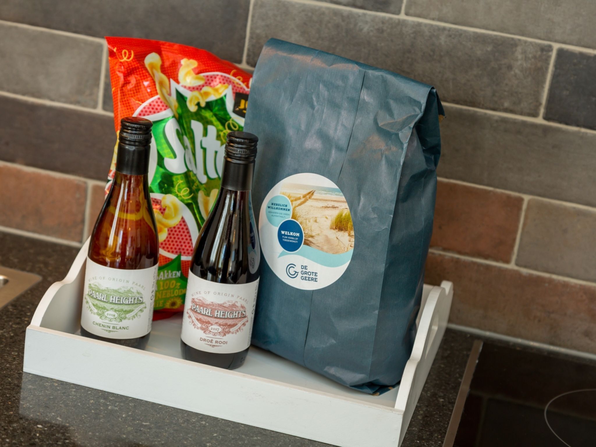 A tray with two bottles of wine, a bag of chips, and a bag of groceries.