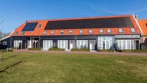 Ein modernes Gebäude mit flachem Dach, zahlreichen Fenstern und einem gepflasterten Weg zum Eingang.