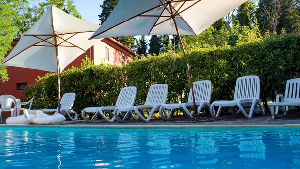 A poolside area with lounge chairs and umbrellas. - Peaceful Apartment, Ghizzano (Peccioli)