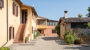 A narrow cobblestone street flanked by traditional buildings with a gravel courtyard. - Belvilla by OYO Selvatello Laura Trilo Cinque (Casole d'Elsa)