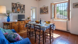 A dining area with a table set for four, a television, and artwork on the walls. - Belvilla by OYO Selvatello Laura Trilo Cinque (Casole d'Elsa)
