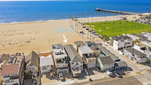 Uma área residencial costeira com casas, uma praia e um cais.