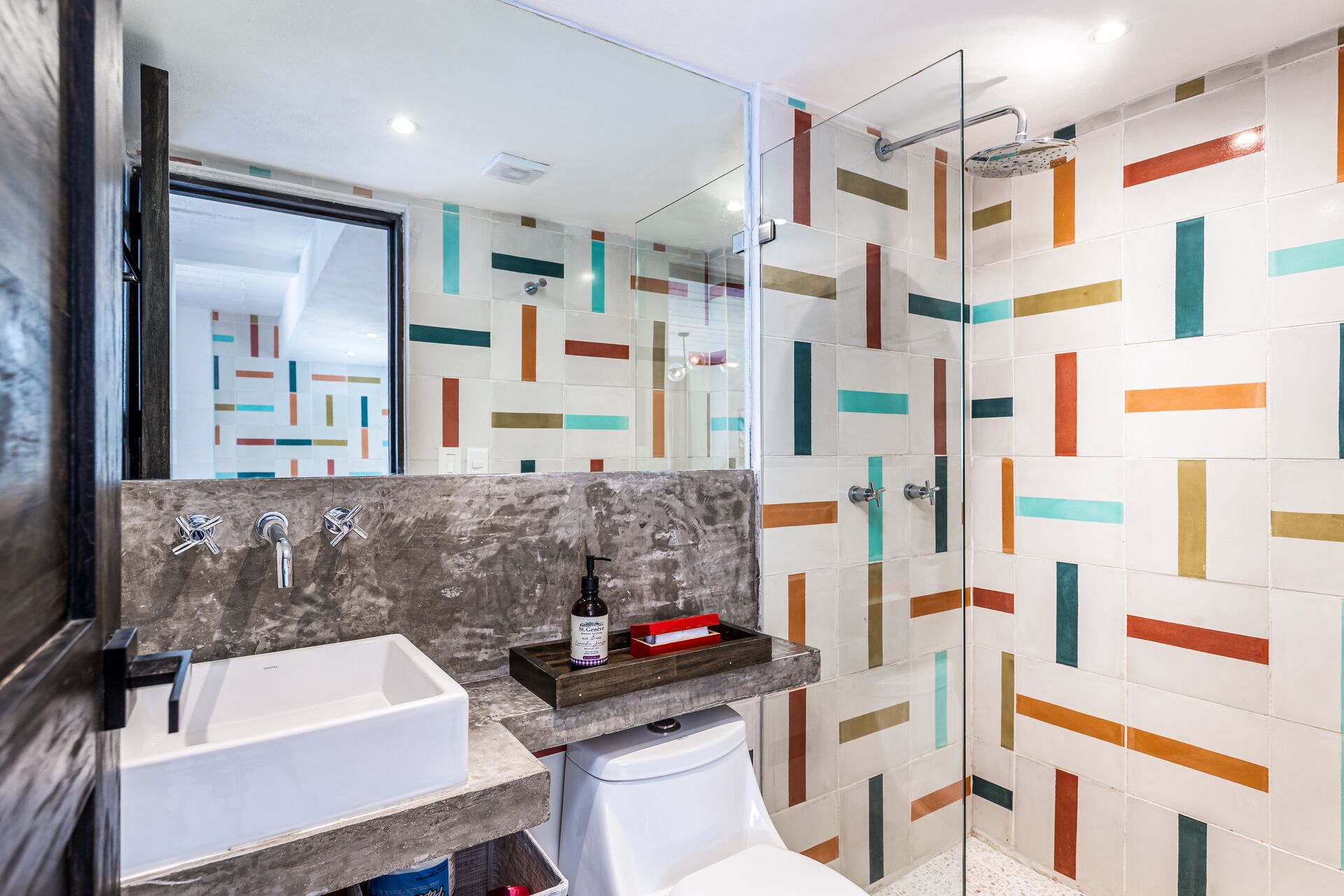 A modern bathroom with a glass shower enclosure, a white sink, and a marble countertop.