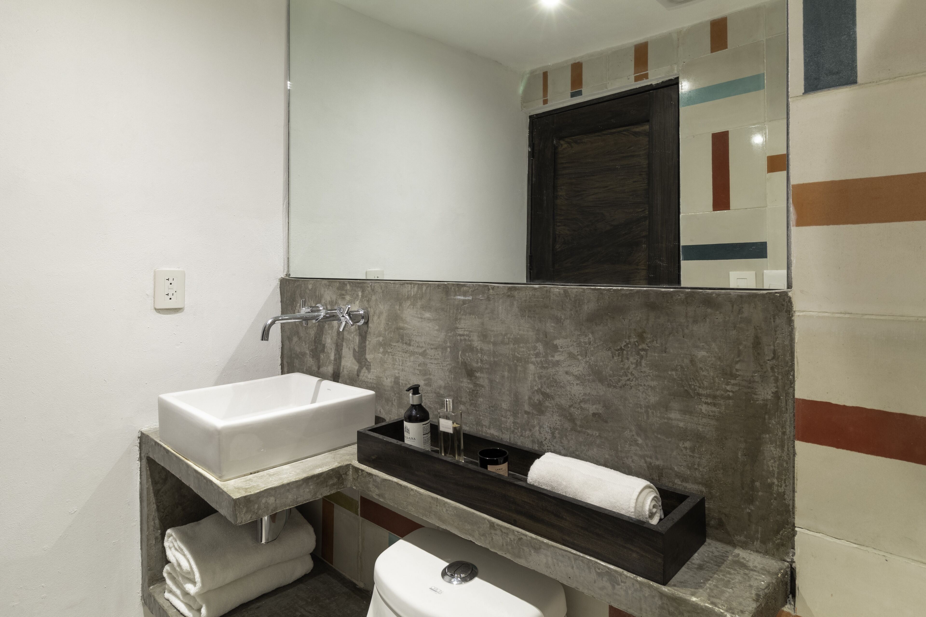 A modern bathroom with a white sink, dark countertop, and a mirror above.
