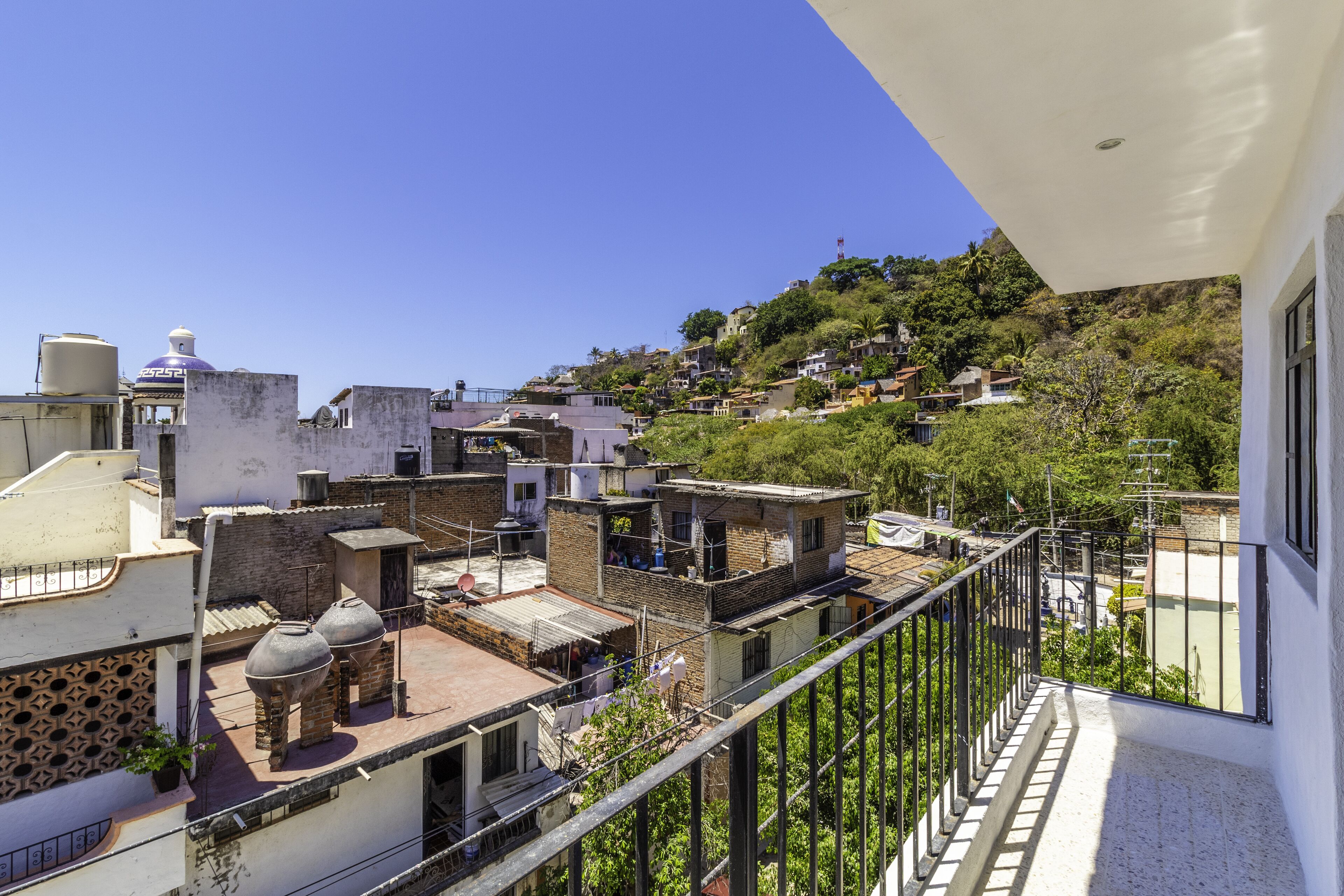 A residential area with a white building featuring a balcony with a metal railing.