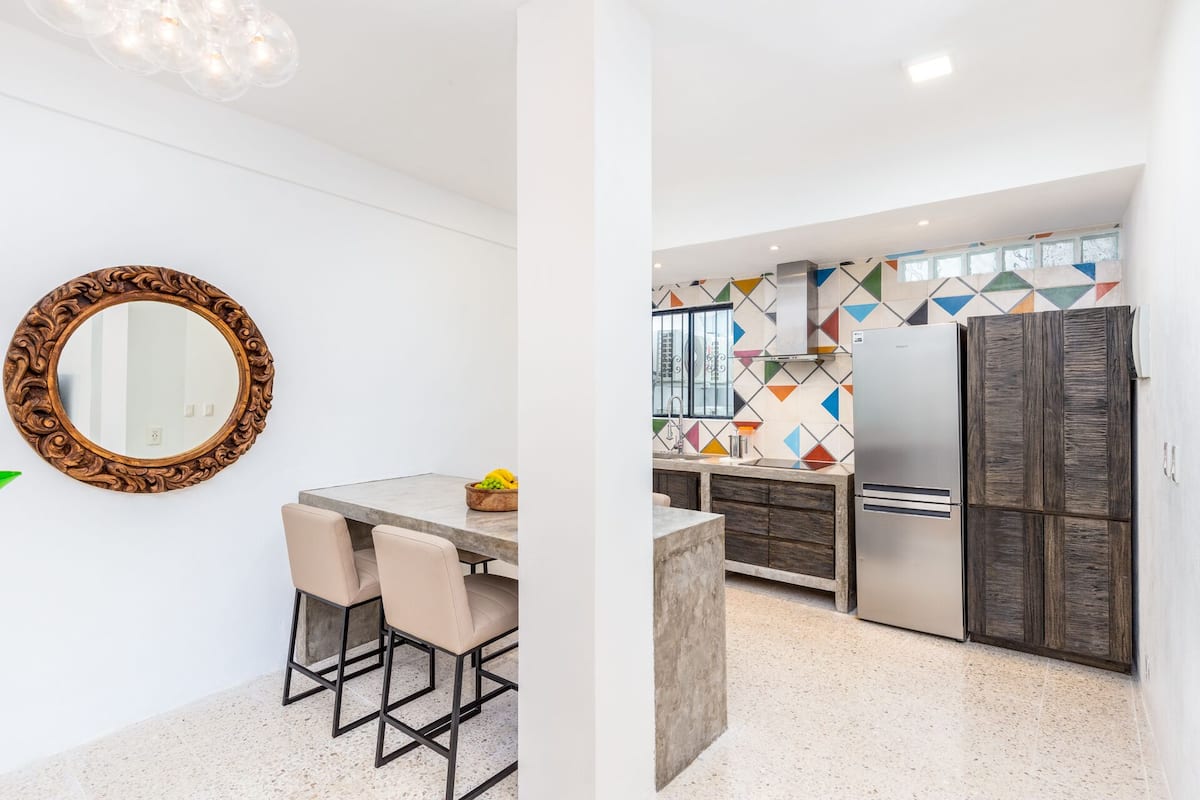 Une cuisine moderne dotée d’un îlot central, d’un réfrigérateur et d’un revêtement mural à motifs géométriques.
