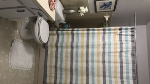 A bathroom with a striped shower curtain, a white sink, and a toilet. - On top of the world condo  (Clearwater)