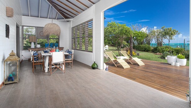 A spacious room with a large window overlooking a lush garden and the sea. - LAGON BLANC (LE VAUCLIN)