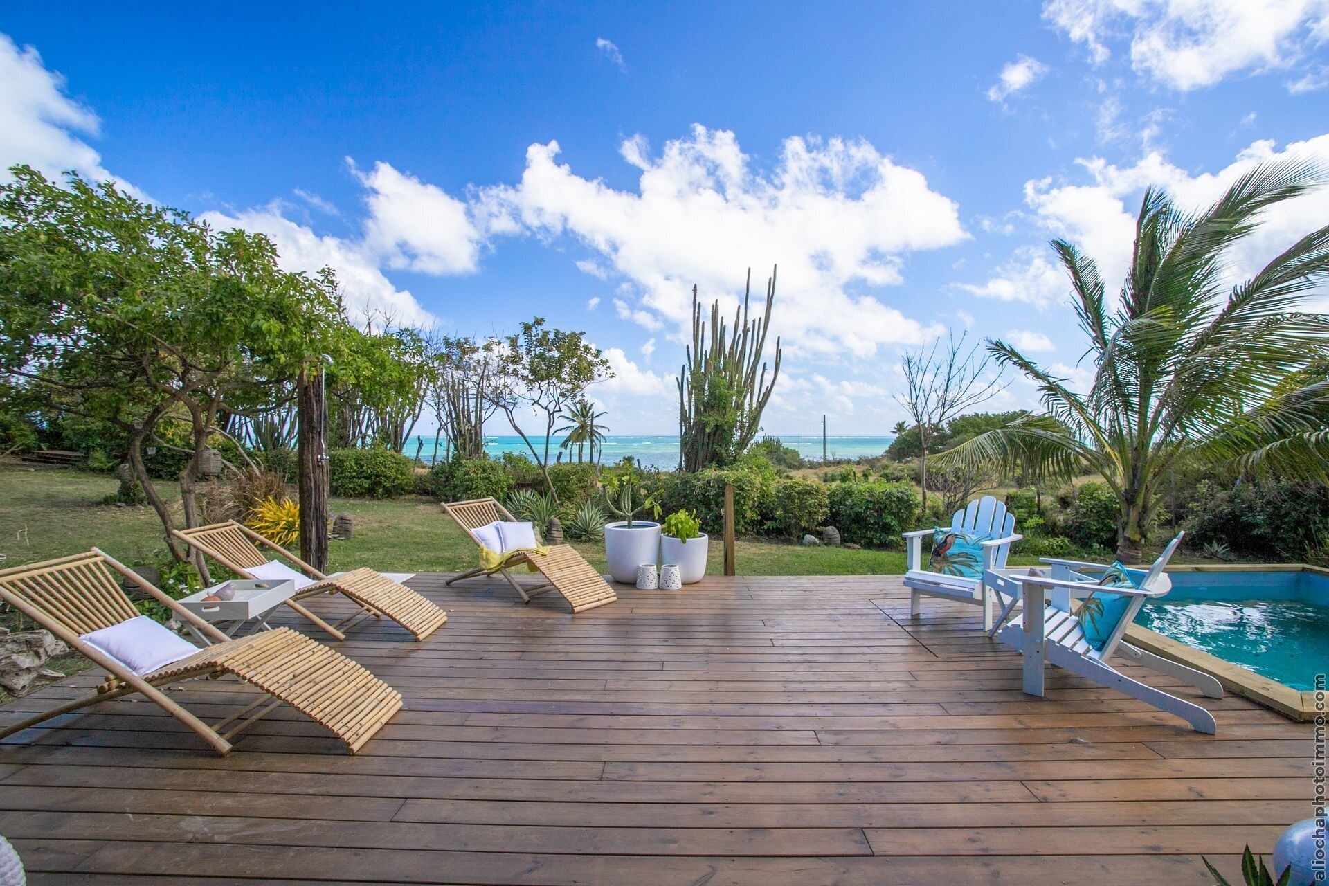 A wooden deck with lounge chairs and a pool.