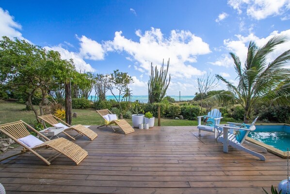 A wooden deck with lounge chairs and a pool.