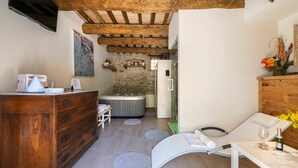 Un bagno moderno con un mobile vanitario in legno, cabina doccia in vetro e un angolo relax con tavolo e sedia.