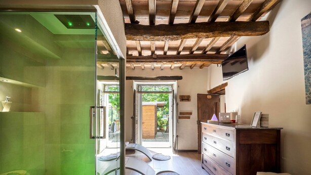 Un bagno moderno con cabina doccia in vetro, pavimento in legno e una panca di legno.