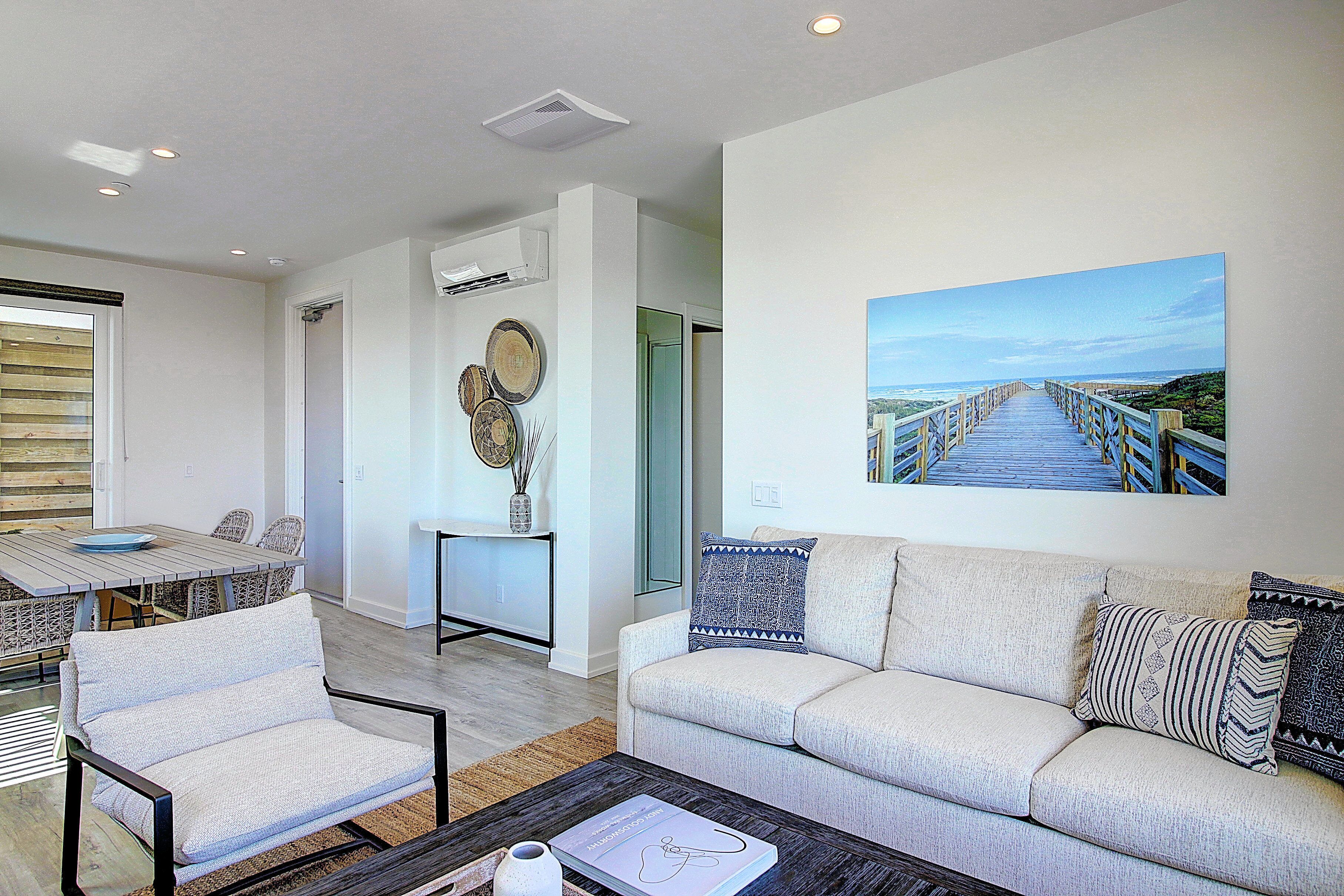 A modern living room with a sofa, armchairs, a coffee table, and a painting of a bridge.